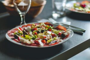 A plate of fresh salad topped with black olives and sliced meats.
